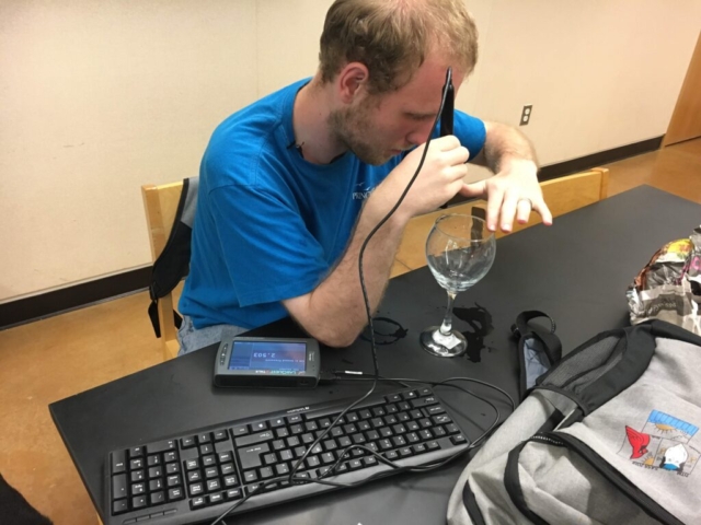 A student uses the sound pressure sensor to compare the tones from two wine glasses filled with water at different levels
