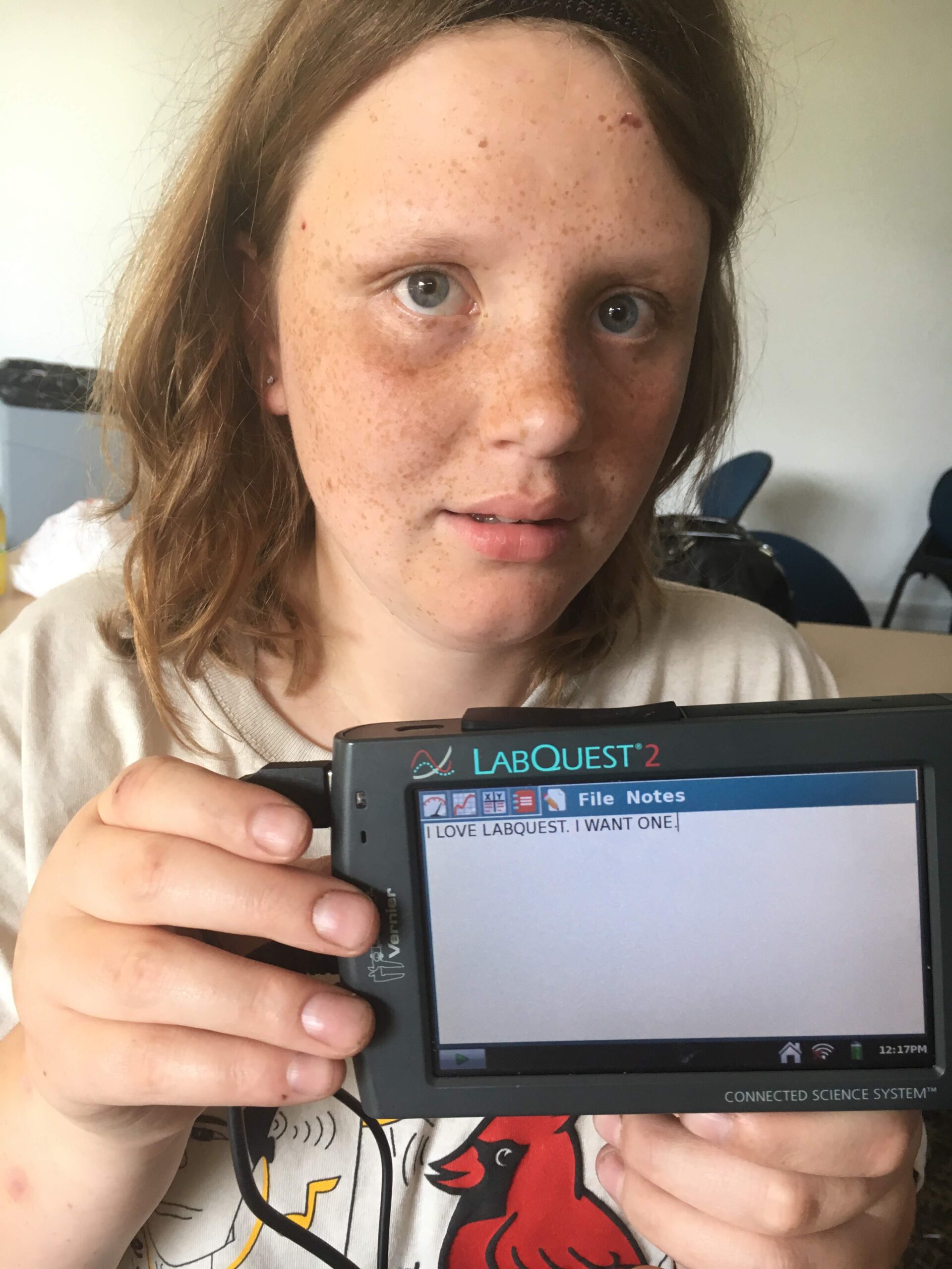 A student holding LabQuest notes page that reads "I love LabQuest. I want one." in all caps