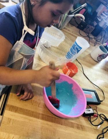A young girl makes a blue slime mixture